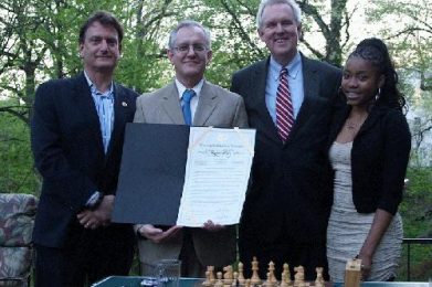 L to R: Marc Rotenberg, David Mehler (holding the “Chess in the Schools Day” resolution) Councilmember Tommy Wells, Rochelle Balantyne.